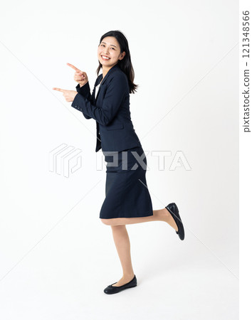 Full-body portrait of a young woman in a suit pointing to the side Full-body portrait of a young woman in a suit pointing to the side 121348566