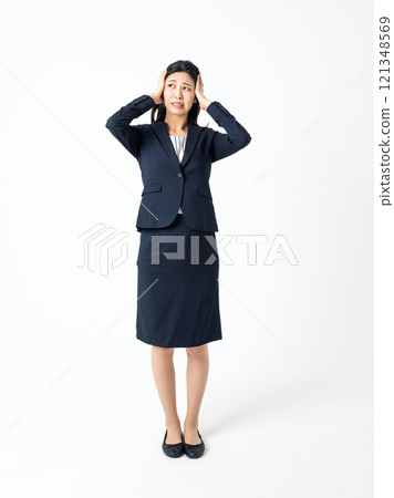 A young woman in a suit holding her head with both hands 121348569