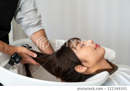 A female customer having her hair washed by a male staff member 121349101