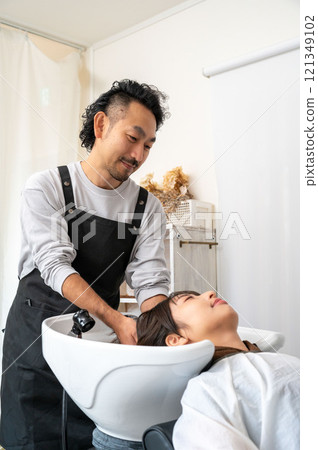 A female customer having her hair washed by a male staff member 121349102
