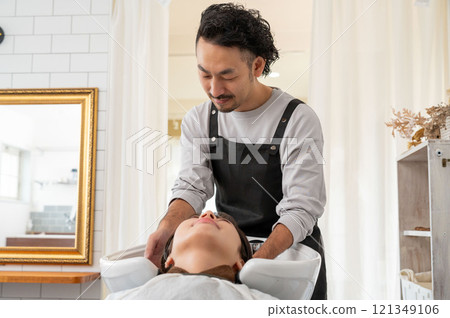 一名女顧客正由一名男工作人員洗頭 121349106