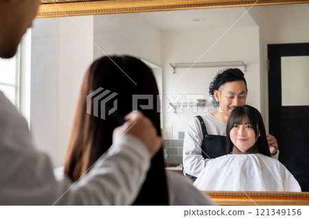 A female customer consulting a male staff member about her hair A female customer consulting a male staff member about her hair 121349156
