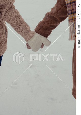 women holding hands in a snowy forest wearing knitted gloves 121349469