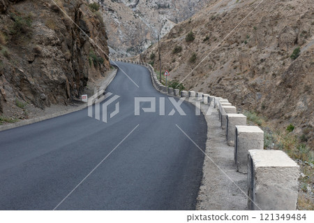 Asphalt road winding along Fan Darya river in Tajikistan's mountainous terrain 121349484