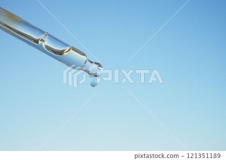 Close-up of a Droplet from a Pipette Against a Clear Blue Sky 121351189