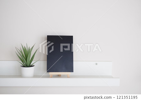 Stylish Minimalist Home Decor Featuring a Black Notebook and a Green Plant Stylish Minimalist Home Decor Featuring a Black Notebook and a Green Plant 121351195