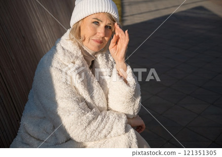 Elegant senior woman relaxing outdoors in winter clothing Elegant senior woman relaxing outdoors in winter clothing 121351305