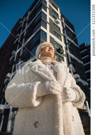 Smiling senior woman wearing winter clothes standing near modern building Smiling senior woman wearing winter clothes standing near modern building 121351306