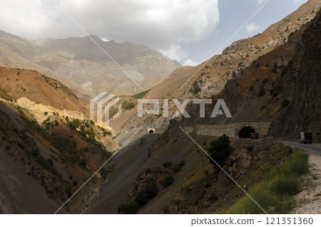 Beautiful mountain tunnels on a road in Tajikistan with rugged terrain and dramatic skies Beautiful mountain tunnels on a road in Tajikistan with rugged terrain and dramatic skies 121351360