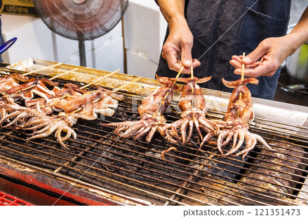 Close-up of the vendors grilling squid skewers at the night market in Taiwan.  121351473