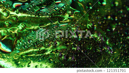 Glowing dew. Moisture metal. Green defocused illuminated shiny area covered with water drops foil effect. Smooth humidity glass background texture. 121351701
