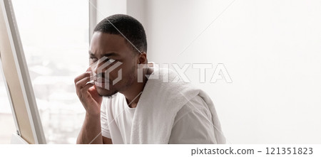 Acne problem. Skincare routine. Zit treatment. Cosmetic dermatology. Unhappy disappointed man touching dry face skin looking in mirror on white empty space background. Acne problem. Skincare routine. Zit treatment. Cosmetic dermatology. Unhappy disappointed man touching dry face skin looking in mirror on white empty space background. 121351823