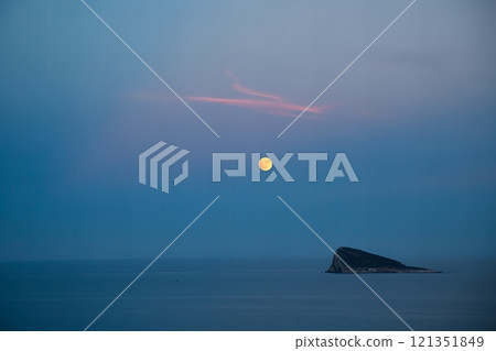 Serene full moon over calm ocean at dusk with small island in Benidorm, Spain. 121351849