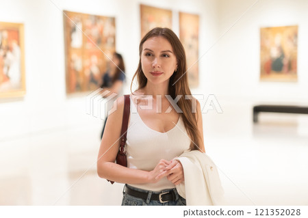 Girl view pictures and icons in museum hall 121352028