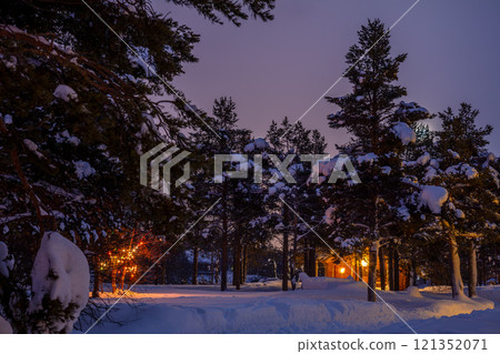 Illuminated Log Cabin and Garland in the Night Snowy Forest 121352071