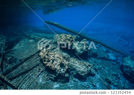 Sunken logs with rocks underwater in crystal blue lake with fresh water 121352454