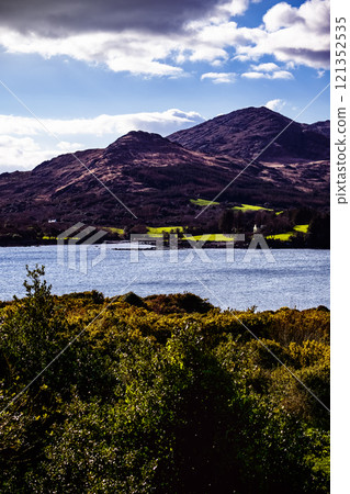 A panoramic shot of a blue body of water with a mountain range in the background. 121352535