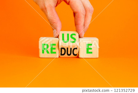 Reuse or reduce symbol. Concept words Reuse Reduce on wooden block. Beautiful orange table orange background. Businessman hand. Business reuse or reduce concept. Copy space. 121352729
