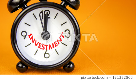 Investment symbol. Concept word Investment on beautiful orange paper. Beautiful orange paper background. Black alarm clock. Business investment concept. Copy space. Investment symbol. Concept word Investment on beautiful orange paper. Beautiful orange paper background. Black alarm clock. Business investment concept. Copy space. 121352863