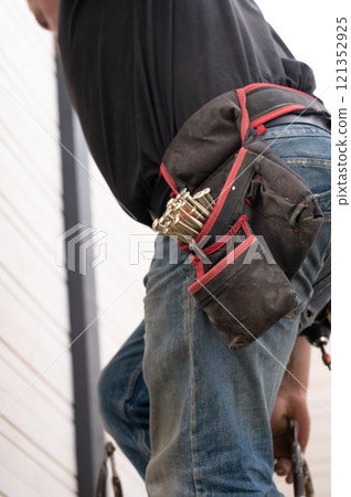 A work belt with pockets for carpentry tools on the worker's waist. A work belt with pockets for carpentry tools on the worker's waist. 121352925