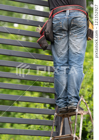 A work belt with pockets for carpentry tools on the worker's waist. 121352927