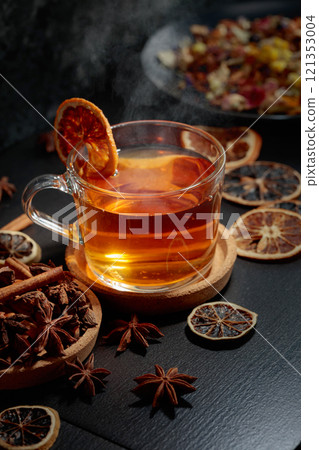 Cup of herbal tea with ingredients and slices of dried orange slices. 121353004