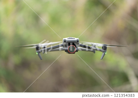 Drone aircraft with blurred fast rotating propellers and video camera flying in air 121354383