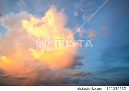 Dramatic sunset landscape with puffy clouds lit by orange setting sun and blue sky. Dramatic sunset landscape with puffy clouds lit by orange setting sun and blue sky. 121354385