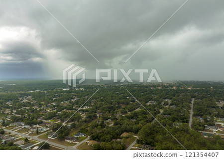 Dark stormy clouds forming on gloomy sky before heavy rainfall over suburban town area Dark stormy clouds forming on gloomy sky before heavy rainfall over suburban town area 121354407