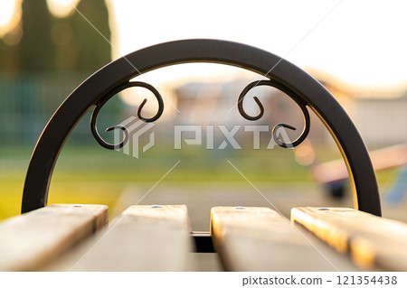 Closeup of wooden park bench with metal handgrip outdoors. Closeup of wooden park bench with metal handgrip outdoors. 121354438