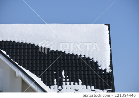 Closeup of house roof top covered with snow in cold winter. Tiled covering of building in wintertime weather Closeup of house roof top covered with snow in cold winter. Tiled covering of building in wintertime weather 121354446