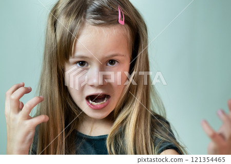 Close up portrait of angry shouting child girl looking aggressively in camera. Close up portrait of angry shouting child girl looking aggressively in camera. 121354465