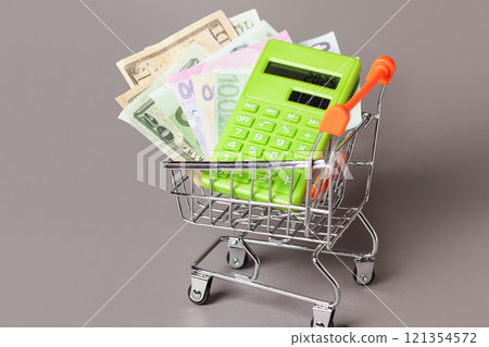 Shopping Cart trolley, Green Calculator, Money. Concept Inflation for Grocery Expenses, Consumerism. Cost of Living. Shopping Cart trolley, Green Calculator, Money. Concept Inflation for Grocery Expenses, Consumerism. Cost of Living. 121354572
