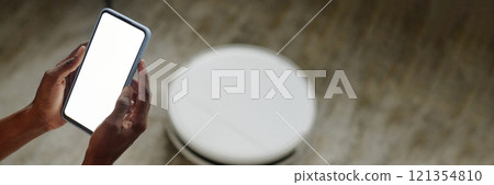 Website banner with unrecognizable woman using smartphone to set brand new robot vacuum cleaner 121354810