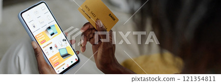 Website banner with unrecognizable woman holding golden credit card and choosing electronic device while doing shopping online Website banner with unrecognizable woman holding golden credit card and choosing electronic device while doing shopping online 121354811