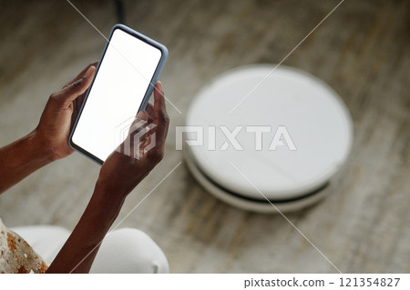 High angle shot of unrecognizable woman launching application for setting robot vacuum cleaner 121354827