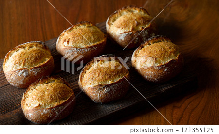 木板和木桌背景上香噴噴的新鮮出爐的黑麥全麥麵包 121355125