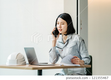 一個穿著工作服的女人用智能手機說話 121355467