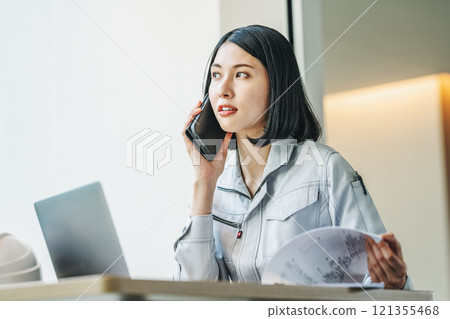 一個穿著工作服的女人用智能手機說話 121355468