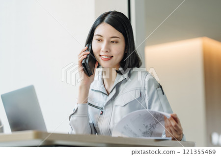 一個穿著工作服的女人用智能手機說話 121355469