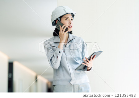 一位年輕的建築經理穿著工作服在智慧型手機上交談 121355488