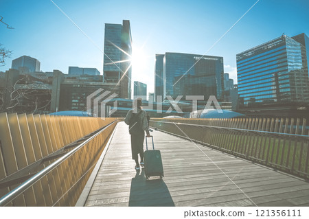 一位攜帶手提箱的女性旅行者的後視圖 一位攜帶手提箱的女性旅行者的後視圖 121356111