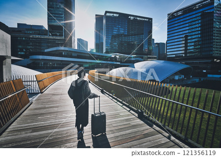 一位攜帶手提箱的女性旅行者的後視圖 一位攜帶手提箱的女性旅行者的後視圖 121356119
