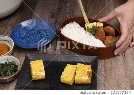 手將米和配菜裝入便當盒中 手將米和配菜裝入便當盒中 121357354