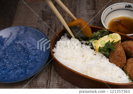 手將米和配菜裝入便當盒中 121357363