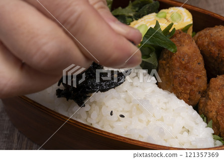 手將米和配菜裝入便當盒中 手將米和配菜裝入便當盒中 121357369