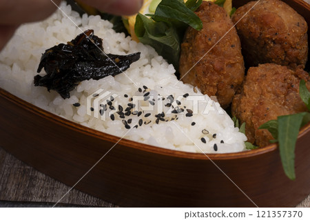 手將米和配菜裝入便當盒中 121357370