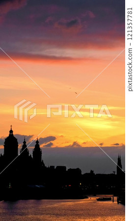 Sunset view of Amsterdam with the church of Saint Nicolas basilica with dramatic sky. Amsterdam, Netherlands Sunset view of Amsterdam with the church of Saint Nicolas basilica with dramatic sky. Amsterdam, Netherlands 121357781