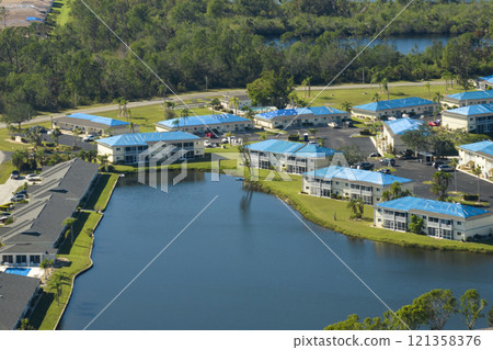 Apartment building roofs covered with blue protective tarp against rain water leaking until replacement of asphalt shingles. Damage done by hurricane winds 121358376