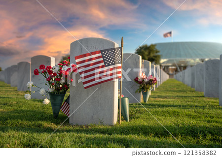 American national military cemetery with rows of white tomb stones with flowers and USA flags on green grass lawn. Memorial Day concept American national military cemetery with rows of white tomb stones with flowers and USA flags on green grass lawn. Memorial Day concept 121358382